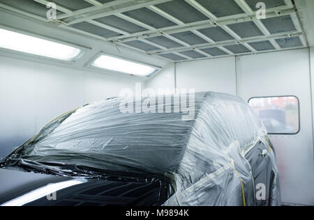 Voiture à l'intérieur d'une cabine de peinture dans un atelier de réparation automobile Banque D'Images