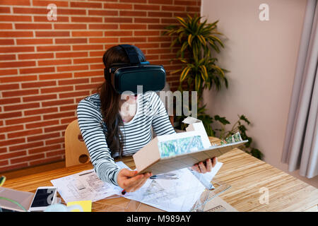 Jeune femme travaillant au bureau d'architecture, à la recherche de modèle avec lunettes VR Banque D'Images