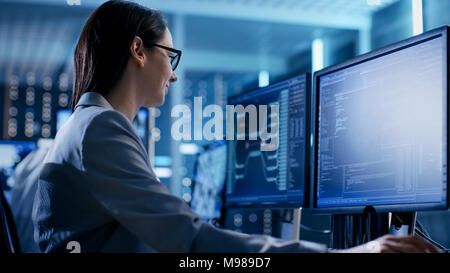 Gros plan d'une femme ingénieur travaillant en salle de surveillance. Elle travaille avec plusieurs écrans. Banque D'Images