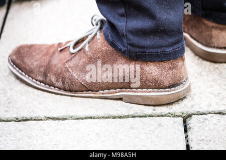 Mans brown suede chaussures sans lacets sur le béton. Banque D'Images