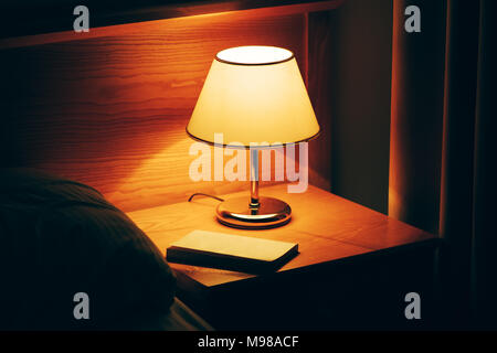 Réserver et vintage lampe sur table de nuit dans la chambre d'hôtel. Chambre de style rétro de l'intérieur. Banque D'Images