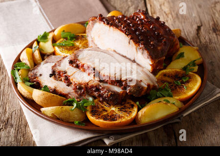 Jambon de noël rôtie avec des tranches d'orange et les légumes sur une assiette sur la table. L'horizontale Banque D'Images