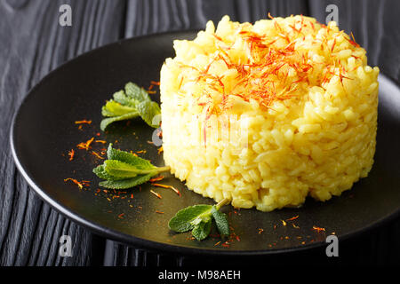 Cuisine italienne végétarienne : risotto au safran et de menthe (risotto alla Milanese) Gros plan sur une plaque horizontale. Banque D'Images