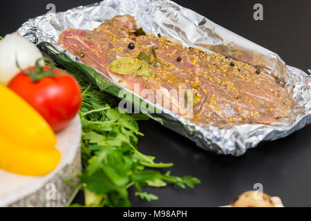 La viande marinée à la moutarde de Dijon, le rôti de poivre et de feuilles de laurier sur une plaque près de légumes sur un fond gris Banque D'Images