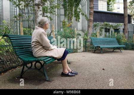 Vieille dame solitaire assis sur banc de parc, à l'écart, Paris Banque D'Images