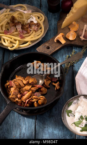 Champignons chanterelles rôties sur le poêle en fonte et les spaghettis sur table en bois rustique Banque D'Images