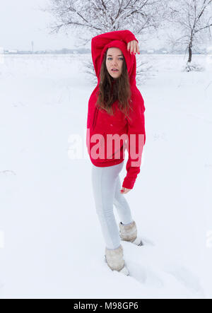 Une jeune femme d'un chandail bleu et blanc short jeans se dresse contre l'arrière-plan d'hiver. Banque D'Images