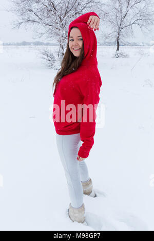 Une jeune femme d'un chandail bleu et blanc short jeans se dresse contre l'arrière-plan d'hiver. Banque D'Images