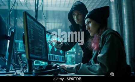Garçon et fille de l'équipe de Hackers Organiser Advanced Attaque de virus sur les serveurs. Ils travaillent ensemble. Lieu est sombre et a l'affichage multiple. Banque D'Images