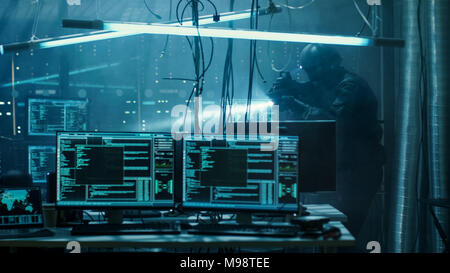 Les Forces Spéciales guerre soldat armé à l'échelle internationale révèle voulait Hacker's hideout. Lair est plein de moniteurs, câbles et a Neon. Banque D'Images