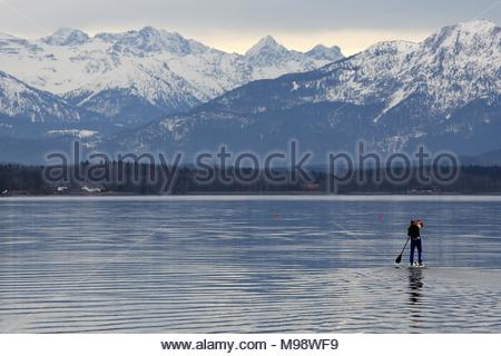 Un homme à bord d'un paddle board fait son chemin vers les Alpes sur le Lac de Starnberg Banque D'Images