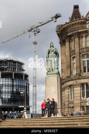 Crans sur la construction des toits de Birmingham, West Midlands, Royaume-Uni. Un groupe de visiteurs ont leur photo prise sous la statue de la reine Victoria. Banque D'Images