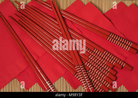 Baguettes laquées rouge avec rouge serviettes papier sur un napperon de bambou Banque D'Images