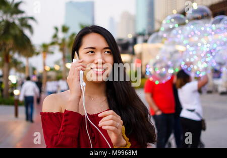 Fille à l'aide de téléphone pendant la charge sur l'extérieur de la banque d'alimentation Banque D'Images