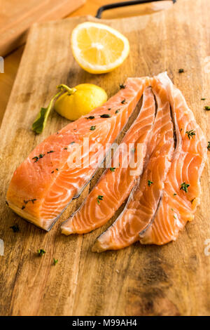 Filet de saumon, filets de sashimi tranches brutes la préparation et prêts à manger rustique en bois sur une planche à découper - orange - citron pain brun Banque D'Images