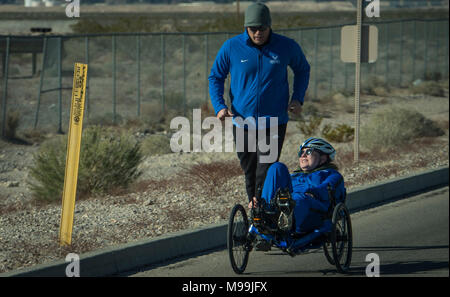 Un coach s'exécute avec un guerrier blessé sportif durant la compétition de cyclisme à la 5e Air Force blessés cliniques sur la base aérienne Nellis, Nevada, 24 février 2018. Les essais cliniques sont un événement sportif adapté visant à promouvoir le bien-être mental et physique des personnes gravement malades et blessés militaires et anciens combattants. (U.S. Air Force Banque D'Images