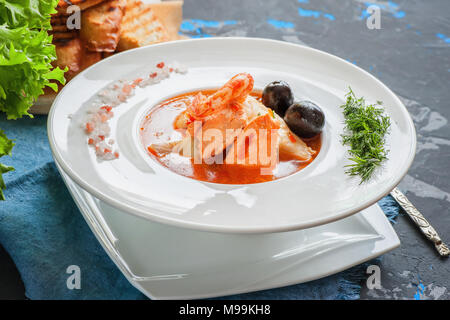 Soupe de poisson française Bouillabaisse aux fruits de mer, filet de saumon, crevettes, saveur riche, délicieux dîner dans un beau plat blanc. Close up. Banque D'Images