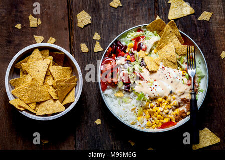 Taco salad bowl avec du riz, du maïs, du chili con carne, haricots rouges, la laitue iceberg, la crème sure, croustilles, tomates Banque D'Images