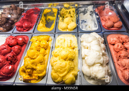 La crème glacée yogourt congelé colorées rouge jaune servant de comptoir avec de nombreuses saveurs scoopable, sorbet, chocolat, garnitures Banque D'Images