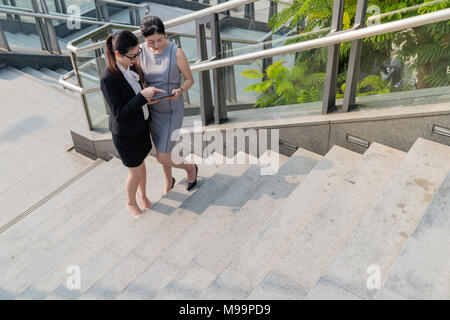 Sur une vue à la baisse.Deux office lady regardant une tablette et regarder des vidéos ensemble. Banque D'Images