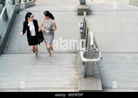Une dame d'affaires est l'introduction d'une office lady boss superviseur portant une tablette avec un geste. Ils sont à pied sur l'escalier. Sur une vue ci-dessus. Banque D'Images