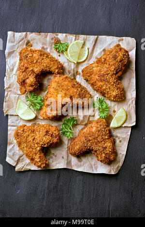 Ailes de poulet pané frit épicé sur papier sur fond noir foncé. Haut de la vue, télévision lay Banque D'Images