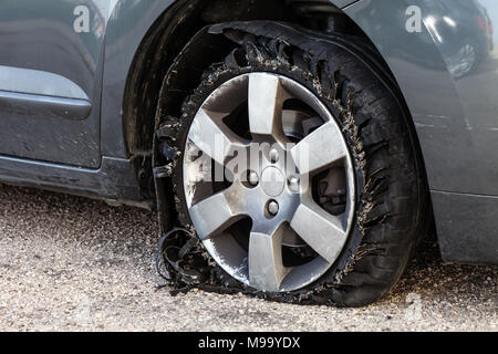 Détruit en épingle avec des pneus déchiquetés, éclatée et caoutchouc endommagé sur un suv moderne automobile. Des pneus à profil plat sur une jante en alliage, éventré Banque D'Images