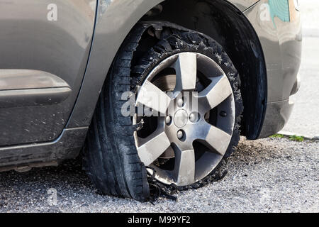 Détruit en épingle avec des pneus déchiquetés, éclatée et caoutchouc endommagé sur un suv moderne automobile. Des pneus à profil plat sur une jante en alliage, éventré Banque D'Images