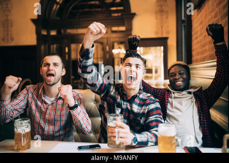 Heureux les fans de football ou des amis masculins de boire une bière et célébrer la victoire à bar ou pub Banque D'Images