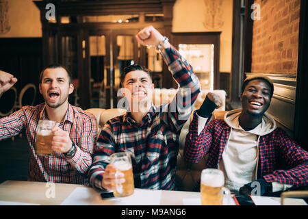 Heureux les fans de football ou des amis masculins de boire une bière et célébrer la victoire à bar ou pub Banque D'Images