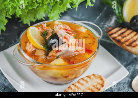 Soupe de poisson française Bouillabaisse aux fruits de mer, filet de saumon, crevettes avec une saveur riche, avec des croûtons. Délicieux dîner dans une plaque de verre transparent. C Banque D'Images