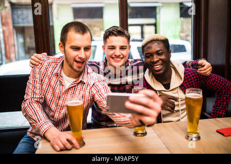 Cheerful vieux amis s'amusant de prendre de la bière à boire et selfies dans un pub. Banque D'Images