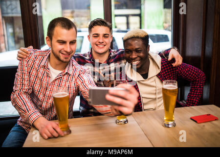 Cheerful vieux amis s'amusant de prendre de la bière à boire et selfies dans un pub. Banque D'Images