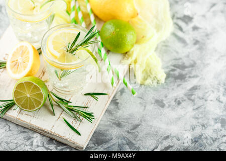 Cocktail sans alcool froid limonade ou avec du citron, du romarin et de la glace dans des verres en verre sur un fond clair. Banque D'Images