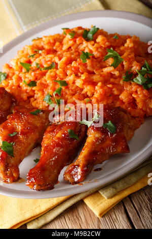 Riz Jollof nigériane classique avec des ailes de poulet frit gros plan sur une assiette. La verticale Banque D'Images