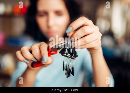 Maître féminin avec une pince à la main faisant earrings Banque D'Images