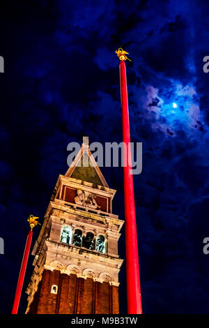 Le Campanile de la Place St Marc avec hampes rouges, le beffroi et la flèche pyramidale avec détail de lion ailé et allumé en arcades du clocher Banque D'Images