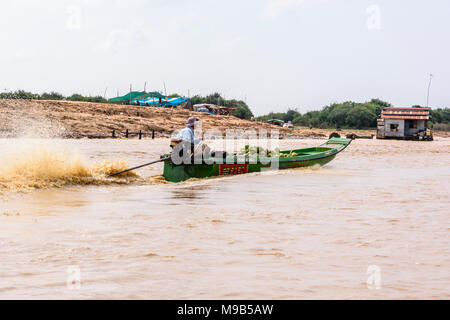 Un homme conduit un bateau à moteur sur la rivière de Siem Reap, Cambodge. Banque D'Images