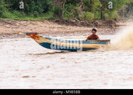 Un homme conduit un bateau à moteur sur la rivière de Siem Reap, Cambodge. Banque D'Images