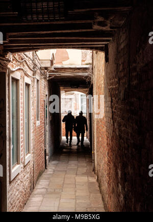 Deux hommes à pied à travers un passage étroit à Santa Croce, Venise Banque D'Images