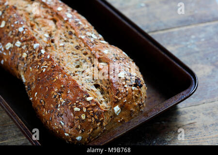 Pain rustique, pain de grains entiers dans la lèchefrite sur table en bois Banque D'Images