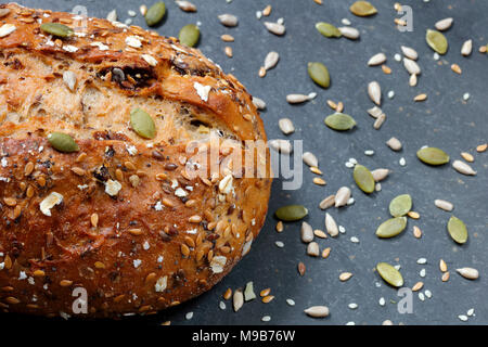 Close up of pain grains rustiques en pain cuisson sur ardoise de table en graines dispersées Banque D'Images