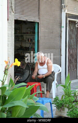 Vieil homme mange des raisins en face de sa maison Banque D'Images