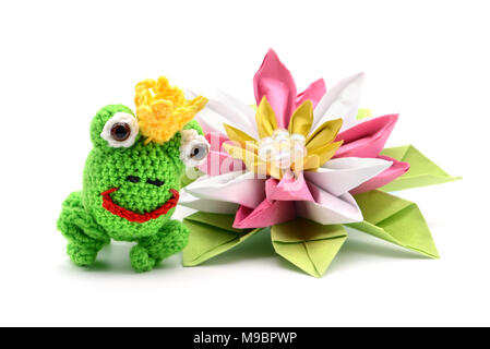 Le roi grenouille au crochet avec conte de couronne et de l'origami nénuphar sur fond blanc. Tinker. Banque D'Images
