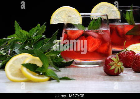 Un verre de limonade aux fraises réfrigérés, les feuilles de menthe, une rondelle de citron avec de la glace Banque D'Images