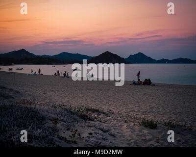 Les baigneurs au coucher du soleil sur une plage de sable de sud Sardaigne, Italie. Banque D'Images