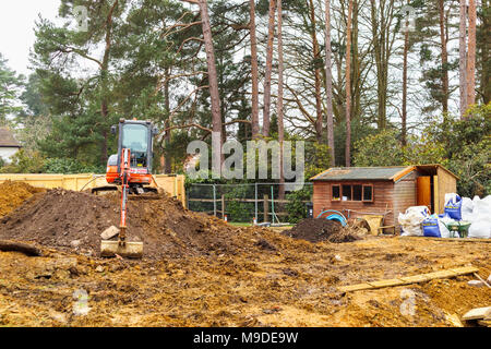 Grosse orange plante lourde mechanical digger garé sur un monticule de terre sur un nouveau développement résidentiel de banlieue construction site Banque D'Images