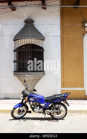 Moto garée devant une maison coloniale avec fenêtre d'ornement à Granada, Nicaragua Banque D'Images