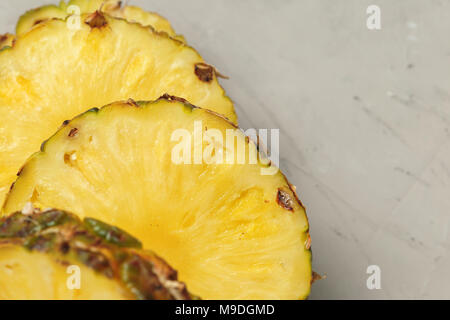 L'ananas frais en tranches sur une planche à découper en bois blanc. Table béton backround. Vue d'en haut Banque D'Images