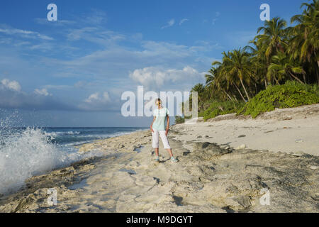 Belle jeune femme à lunettes jaunes sur une plage de corail Banque D'Images